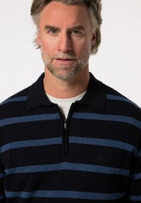 Granatowy i jasnoniebieski pulower w paski z rozpinanym kołnierzem, charakteryzujący się teksturowanym splotem i subtelny logo na klatce piersiowej.