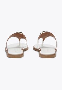 Sandali bianchi con punta aperta e suola marrone, dotati di un accento dorato sulla punta. La parte superiore ha una texture liscia e un design minimalista.