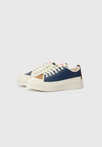 Marine lædersneakers med cremeaccentuer og en tan sidepanel. Har runde snørebånd, en tyk gummisål og en polstret krave.