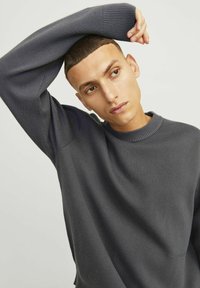 Mørkegrå strikket sweater med ribbet rund hals og manchetter. Har en afslappet pasform og glat tekstur, med subtile mønstre på stoffet.