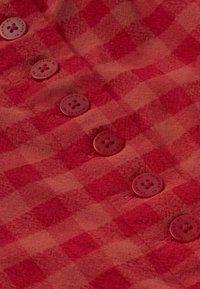 Tissu à carreaux rouge et rose avec cinq boutons rouges, chacun gravé de "THINKING MU" autour des bords.