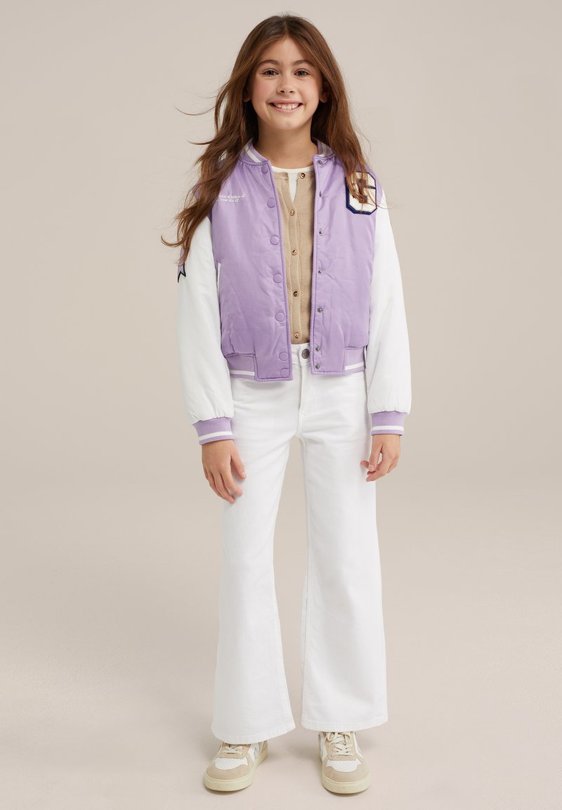 Levandų ir baltas bomberis, su mygtukų užsegimu, riboti rankogaliai, derinamas su kreminio atspalvio marškiniais ir platiomis baltomis kelnėmis, užbaigtas kreminiais sportbačiais.