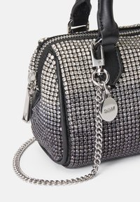 Črna in srebrna torbica, prekrita z majhnimi rhinestones, z zadrgo, zgornjima ročajema in odstranljivim verižnim trakcem.