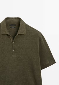 Olivgrön polo t-shirt i texturerad tyg, med klassisk krage, tre knappar och korta ärmar med en avslappnad passform.
