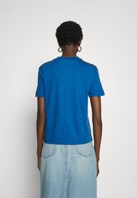 Camiseta azul de manga corta con un clásico cuello redondo. Diseño simple con una textura suave, combinada con una falda de mezclilla azul clara.