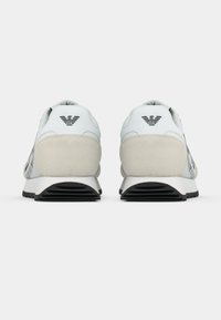 Fehér és világosszürke sneaker cipők velúr részletekkel, texturált hálós panelekkel, logóval a saroknál és fekete gumitalppal. Klasszikus sportos kialakítás.