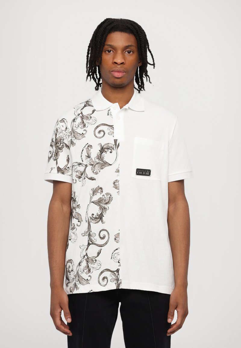 Balta polo krekls ar melnu un bežīgu greznu rakstu vienā pusē, otrā pusē vienkārši balts, ar krūšu kabatu un melnu etiķeti.