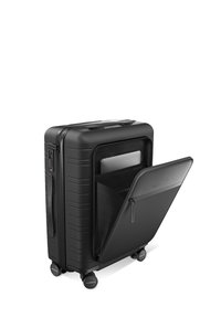 Valise noire à roulettes avec une surface texturée, des coins arrondis, une poignée intégrée et une poche frontale zippée. Conçue pour le stockage d'ordinateur portable.