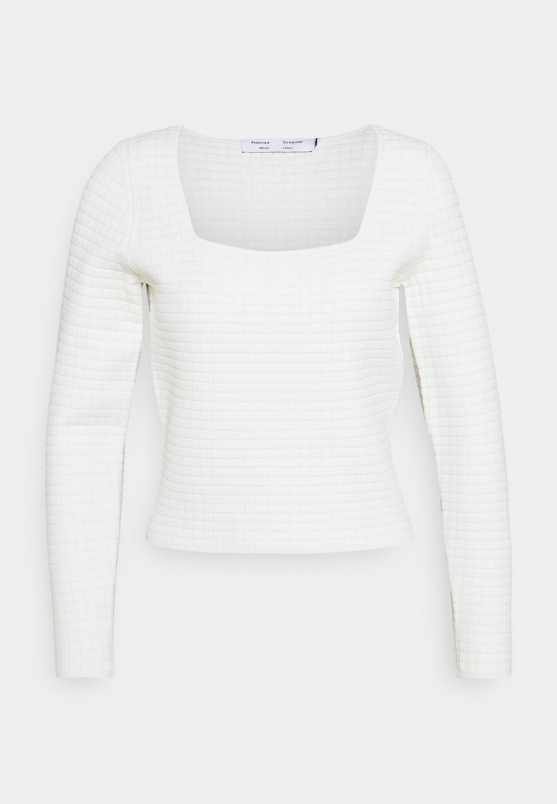 Crop top blanc à manches longues avec encolure carrée et motif quadrillé texturé, silhouette ajustée.