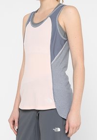 Szary i różowy bezrękawnik sportowy o dopasowanym kroju, z teksturowanymi bocznymi panelami i logo na krawędzi. Miękki, odprowadzający wilgoć materiał.