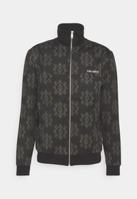 Chaqueta negra con cremallera que presenta un detallado patrón gris, cuello alto y puños acanalados. El nombre de la marca "LES DEUX" está mostrado en el pecho.