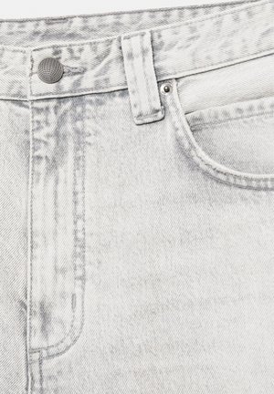 Gros plan sur un jean en denim gris clair montrant un bouton, une boucle de ceinture, une poche avant, un rivet et des coutures détaillées.
