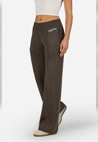 Tmavošedé, voľné tepláky s elastickým pásom a mäkkou textúrou, s malým logom na prednej strane.