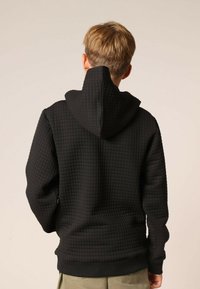 Zwarte hoodie met een gestructureerd, doorgestikt patroon. Voorzien van een hoge kraag met capuchon, lange mouwen en geribbelde boorden aan de mouwen en zoom.