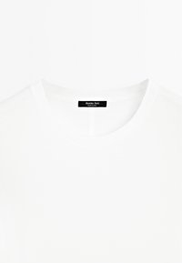 Hvid bomuld T-shirt med rund halsudskæring. Har en sort label bagpå med teksten "Massimo Dutti" og "Made in China".