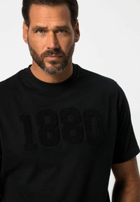 Černé bavlněné tričko s texturovaným, vyvýšeným grafickým prvkem "1880" ve shodné černé barvě. Kulatý výstřih s krátkými rukávy. Hladká textura látky.