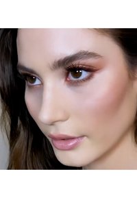 Close-up of a face with warm brown eyes, naturally arched eyebrows, soft pink lips, and smooth skin in a natural makeup look.