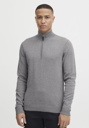 Grey zip-neck sweater in soft knit material with long sleeves and ribbed hem. Features a quarter-length zipper and a textured finish.