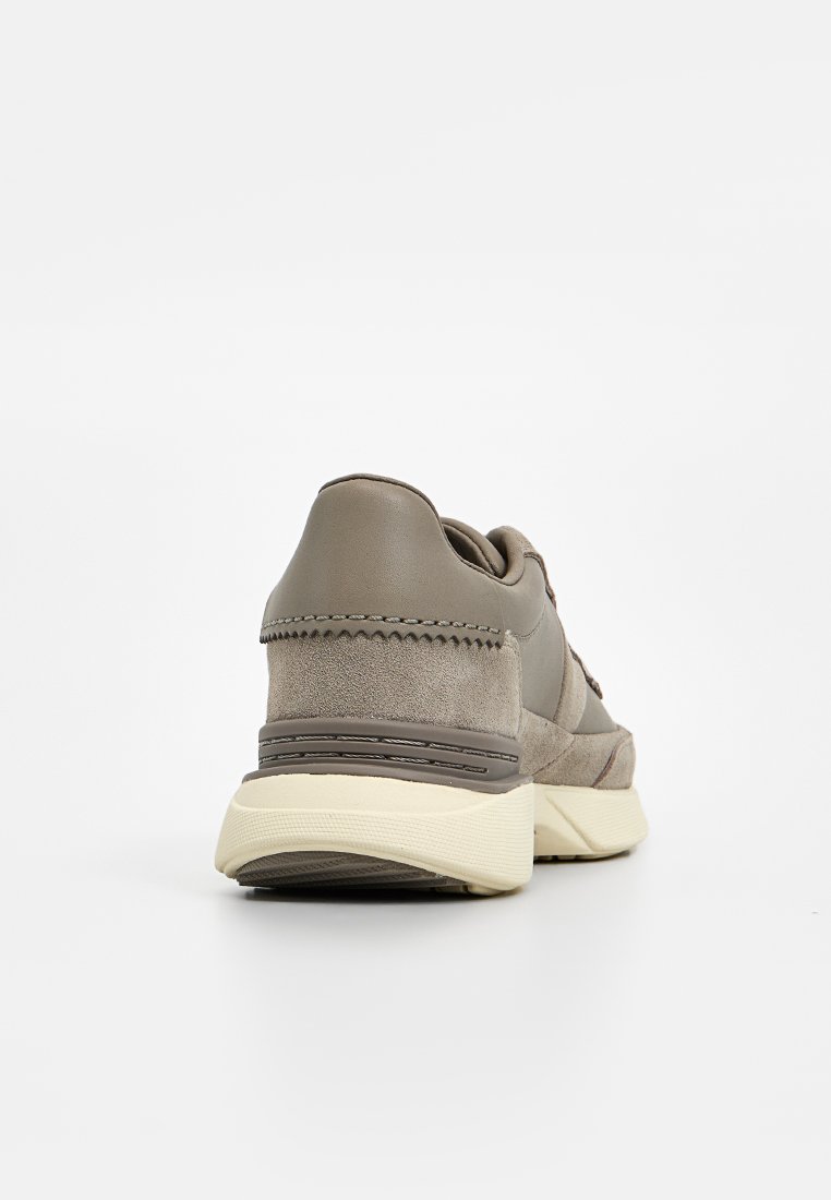 Sneakers in pelle e camoscio marrone chiaro con accenti testurizzati, dalla forma arrotondata e con una suola bianca imbottita. Dettagli di cucitura visibili.