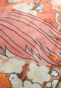 Tela floral que presenta flores rosas con blancas y naranjas. El diseño texturizado incluye contornos verdes y patrones sutiles en toda la tela.