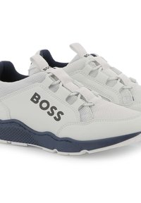 Baskets en maille blanches avec des accents bleu marine, présentant une semelle texturée, un logo sur le côté et des sections de lacets renforcées pour le soutien.