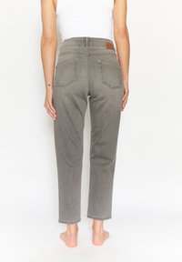 Grå denimjeans med hög midja, rak passform och två bakfickor. Har ett lädermärke vid midjan.