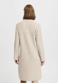 Beiges geripptes Strickkleid, lange Ärmel, mittellang, strukturiertes Material. Einfaches Design mit rundem Kragen und geradem Saum.