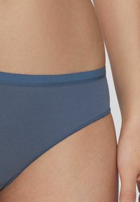 Modré bikini kalhotky z bavlněné směsi s bezešvou konstrukcí, nabízející hladký povrch a střední pas. Jednoduché a čisté okraje.