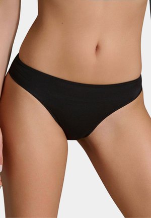 Sezione centrale femminile che indossa mutandine bikini nere semplici su uno sfondo chiaro uniforme.