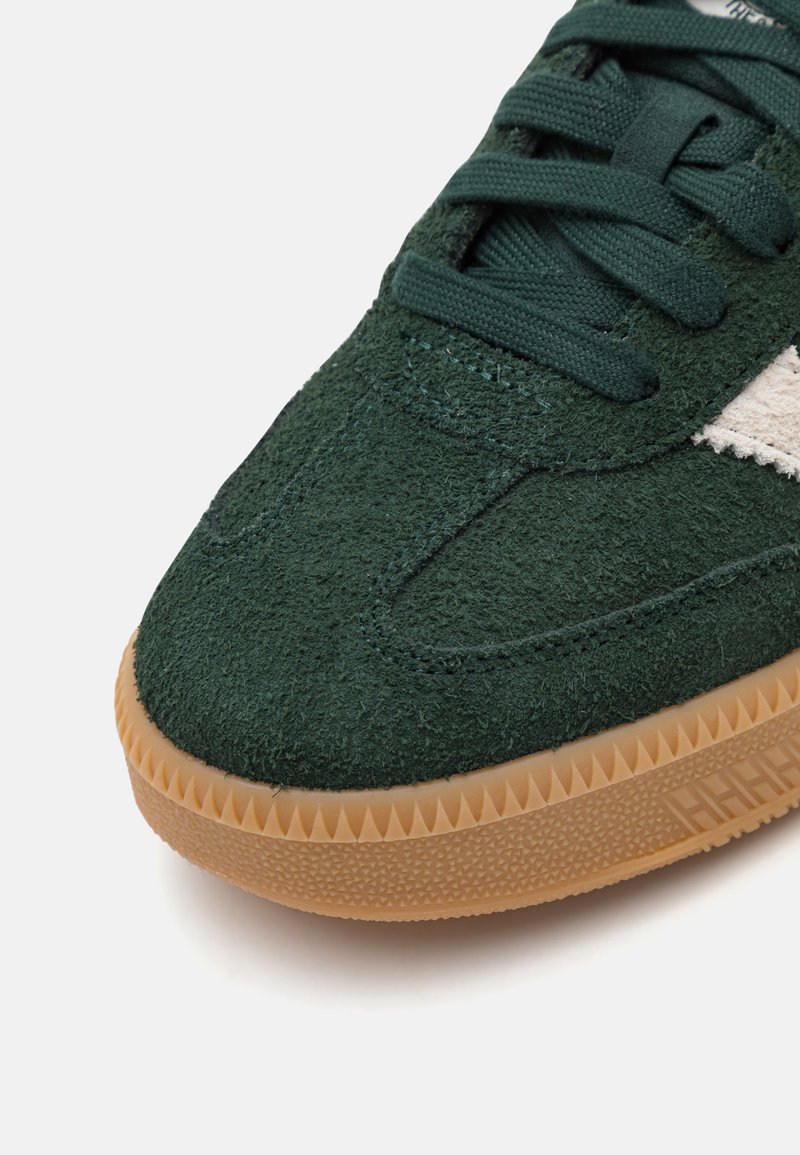 Baskets en daim vert avec un dessus texturé, lacets plats et semelle en caoutchouc gomme présentant un motif en zigzag le long du bord.