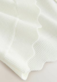 Weißes Strickgewebe mit Rippenstruktur und gewellten Rändern, das ein weiches und glattes Erscheinungsbild mit subtilen Finish-Variationen bietet.