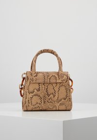 Liten handväska i beige med ormskinnsstruktur, dubbla handtag upptill och kedjedetaljer i bärnstensfärg, uppställd på en vit pelare.