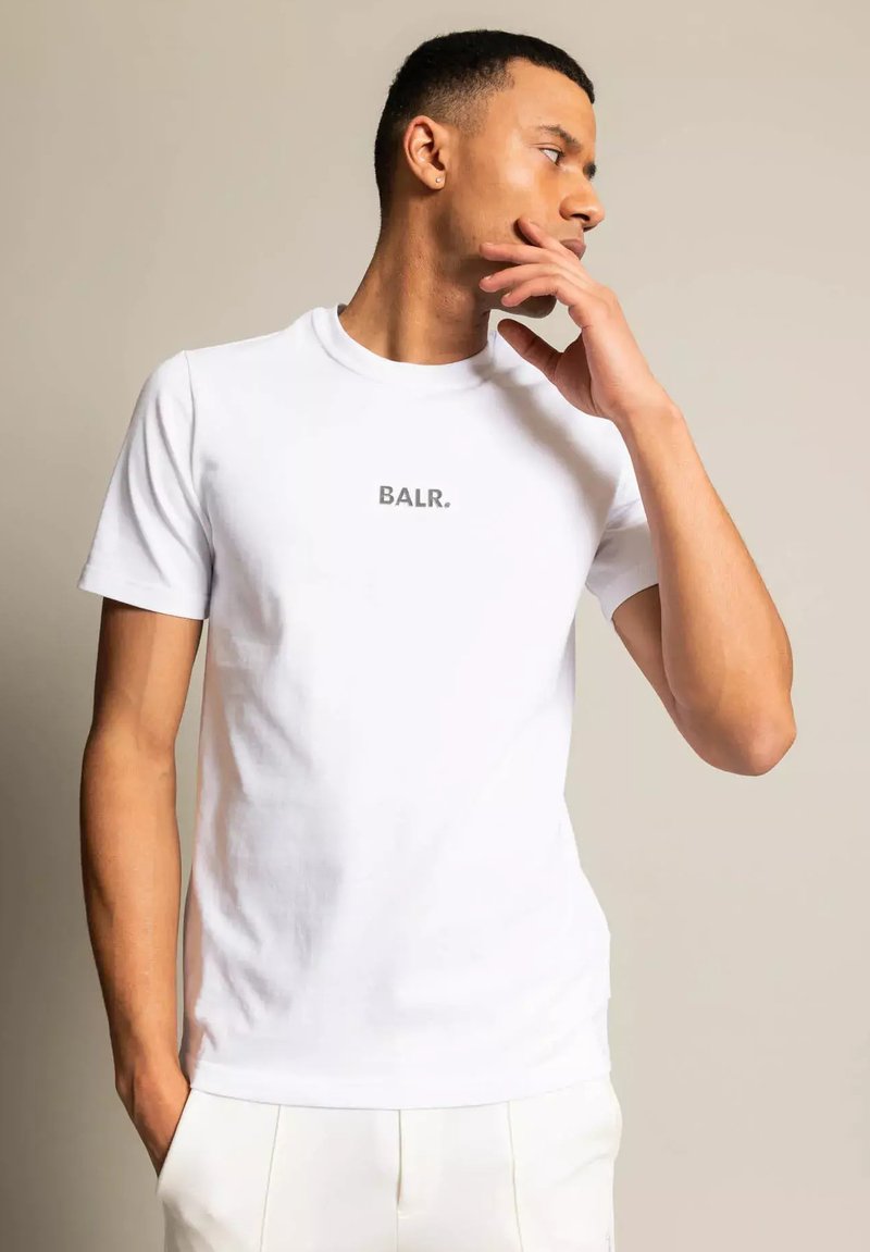 Biała bawełniana koszulka z okrągłym dekoltem, z małym szarym logo "BALR." na piersi. Ma krótkie rękawy i dopasowany krój.