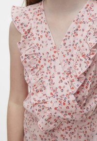 Vestido floral rosa con tirantes rizados y diseño de escote en V, hecho de una tela texturizada con pequeños patrones de flores rojas y azules.