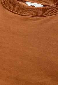 Sudadera marrón con un cuello redondo acanalado y una tela suave y texturizada. El color es uniforme, sin patrones o acentos visibles.