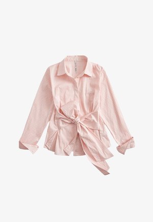 Chemise à manches longues en vichy rose et blanc avec col et grand nœud noué à la taille, poignets boutonnés et ourlet légèrement évasé.