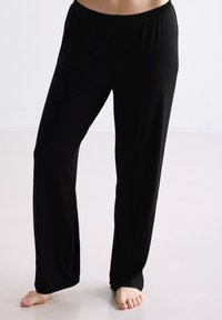 Zwarte, loszittende broek gemaakt van zacht, rekbaar materiaal met een elastische tailleband. Heeft een recht pijp ontwerp en geen zichtbare patronen.
