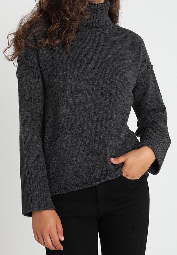 Mörkgrå polotröja med ribbade mudd och nederkant, med ett strukturerat stickmönster och avslappnad passform. Kombineras med svarta byxor.