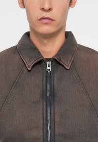 Dark denim jacket with a collar and gray-brown texture, featuring a front metal zipper and contrasting dark zippers; casual design.
