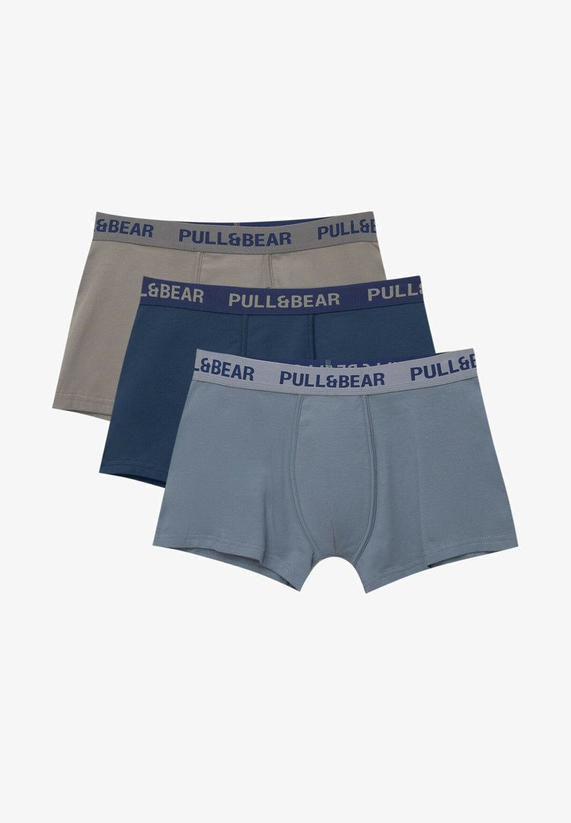 Tre par herrboxershorts i beige, mörkblå och ljusblå. Varje pare har en kontrasterande midja med "PULL&BEAR" i blå urklippt text.