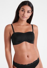 Zwarte strapless beha gemaakt van glad materiaal met een gevormde cupdesign. Verstelbare bandjes en naadloze randen voor een strakke afwerking.