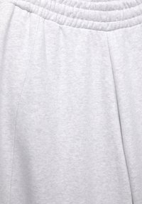 Helle graue Baumwollstoffe mit einem elastischen Bund und subtilen Nahtdetails, die auf legere Jogginghosen oder Shorts hindeuten.