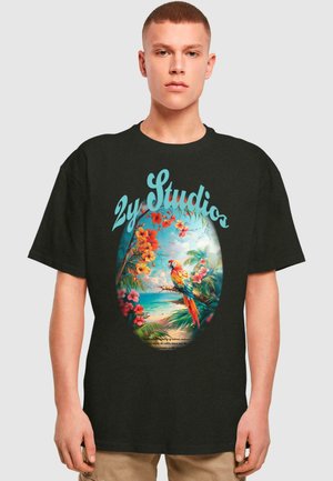 Sort bomulds T-shirt med et farverigt grafisk design af en papegøje blandt tropiske blomster og en strandscene, med tekst "2y Studio" integreret.