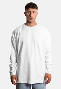 Weißes Langarm-T-Shirt aus weichem Baumwollmaterial, mit rundem Halsausschnitt und lässiger Passform. Keine sichtbaren Muster oder Logos.