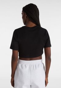 Sort cropped t-shirt med kortærmer, der har en blød tekstur og rund halsudskæring, parret med lysegrå sweatpants.