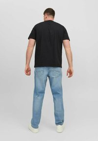 Zwarte katoenen t-shirt met een ronde hals, gecombineerd met lichtblauwe denim jeans. De jeans hebben een relaxte pasvorm en een stikseldetail op de achterzak.