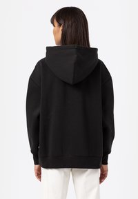 Black oversized hoodie made of soft fabric. Features a large hood, dropped shoulders, and ribbed cuffs. Simple, minimalist design.