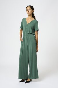 Mono verde de manga corta con escote en V, cintura elástica y diseño de pierna ancha. Tejido suave con bolsillos laterales y ajuste relajado.