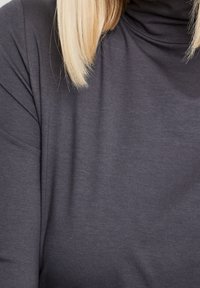 Maglione grigio a collo alto realizzato in un tessuto morbido e leggero con una texture liscia. Presenta una vestibilità comoda e un design di drappeggio sottile.