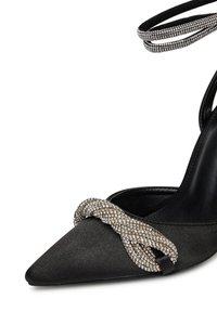 Pantofi cu toc înalt din satin negru, cu vârf ascuțit și o embellisment din rhinestone răsucit pe față, plus curea din rhinestone la gleznă.